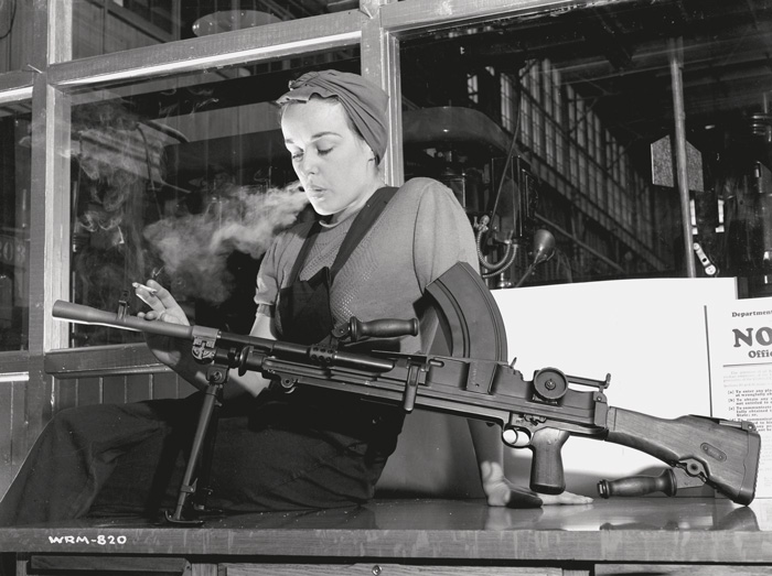 Photographe inconnu / Unknown photographer, Veronica Foster, an employee of John Inglis Co. Ltd. and known as “The Bren Gun Girl” posing with a finished Bren gun in the John Inglis Co. Ltd. Bren gun plant, Toronto, 10 May 1941